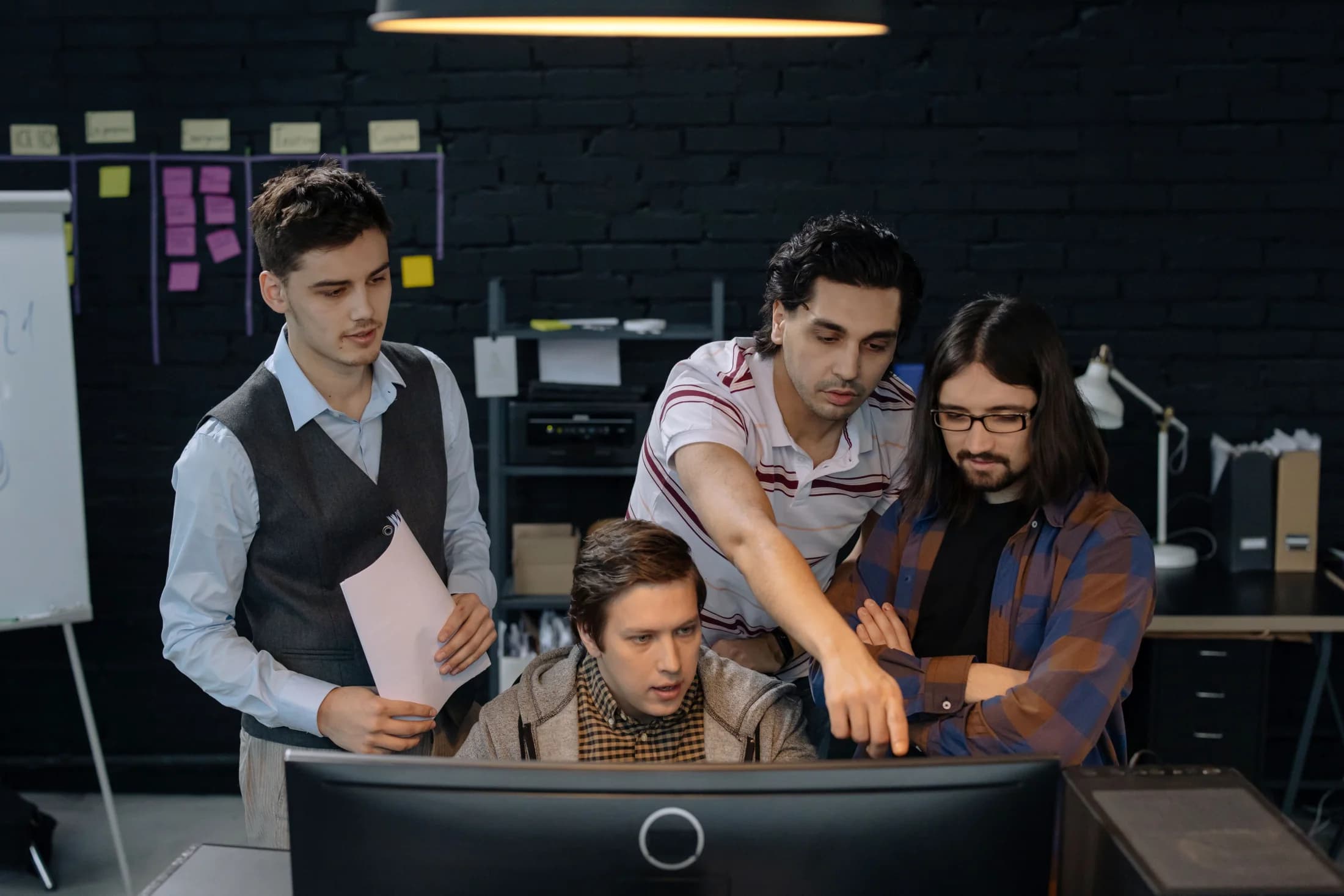 A technical team reviewing work together at a computer