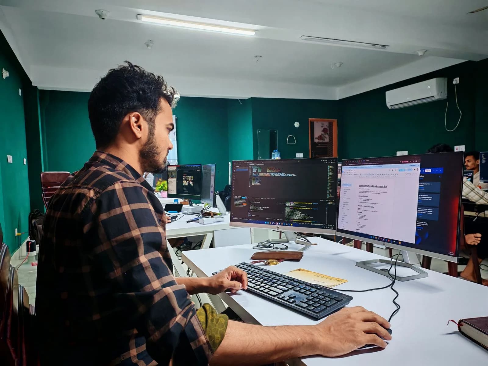 A software developer working across two monitors