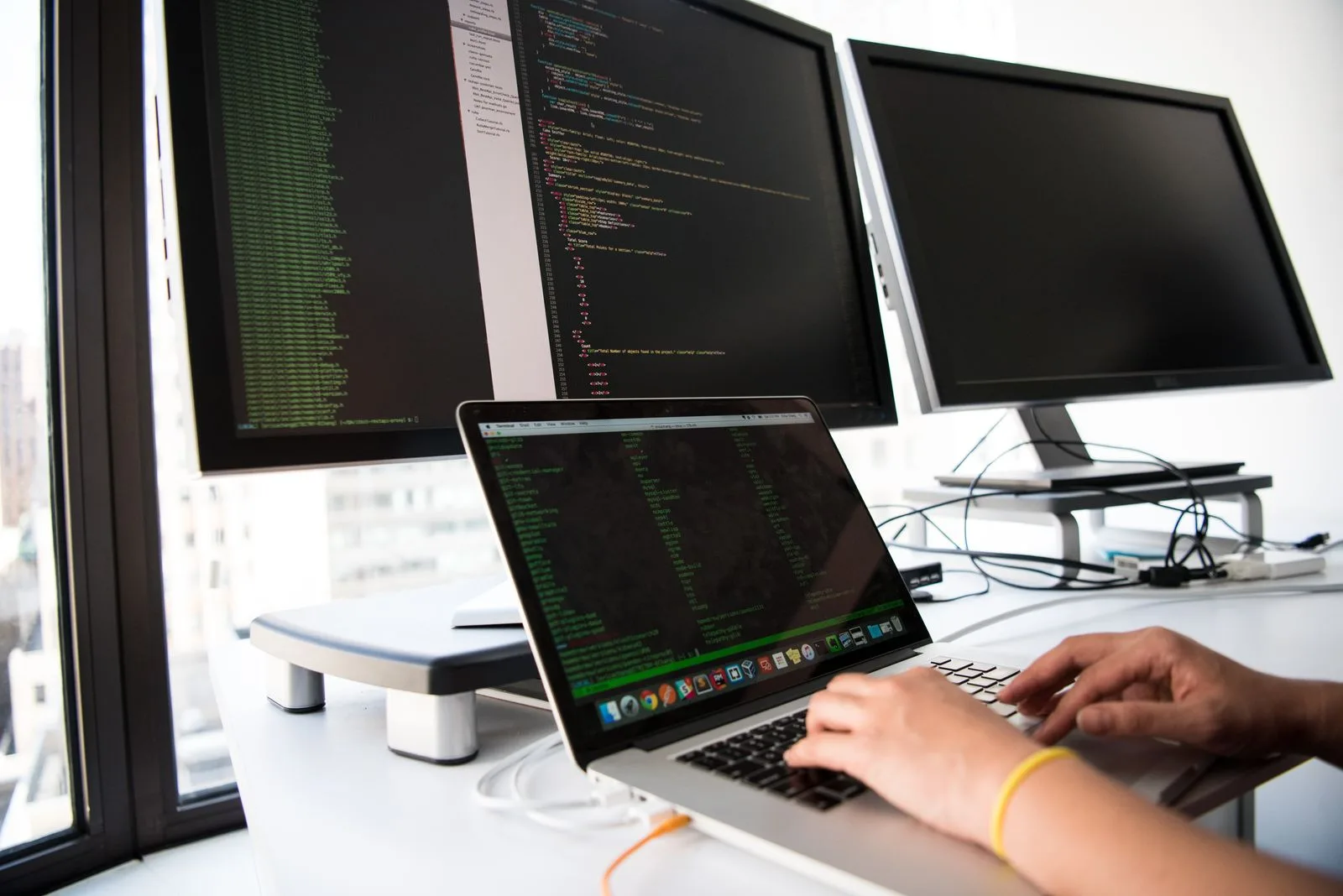 A developer working across a laptop and multiple screens