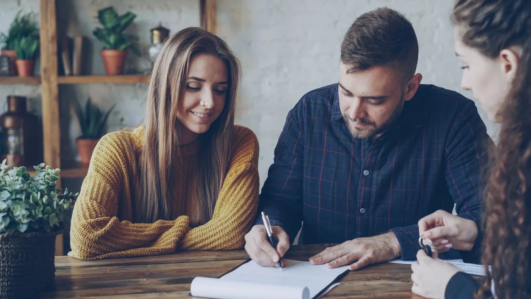 Three professionals reviewing and signing a document together