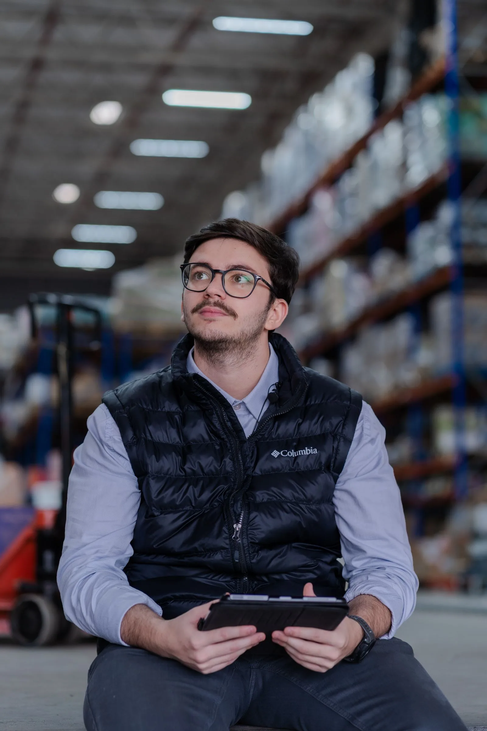 An operations professional using a tablet in a warehouse aisle
